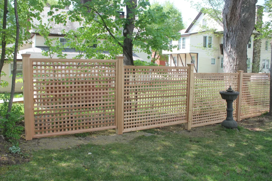 Cedar lattice privacy fence built along a backyard property line.
